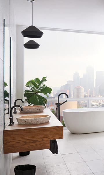 Beautiful bathroom with an overview of the city. Bowl designed faucets and a unique tub with black pendant lighting