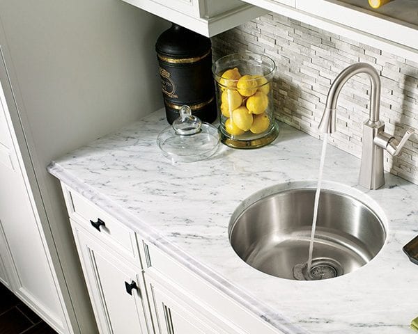 A kitchen sink faucet - circular design with marble counter tops and tile back splash