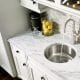 A kitchen sink faucet - circular design with marble counter tops and tile back splash